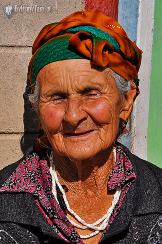 Starsza pani wygrzewająca się przd swoim domem w Karakul